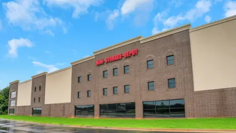 Self-storage facility with brick exterior, large windows, and visible "Mini Storage Depot" sign.