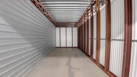 Inside a self-storage unit featuring metal siding and an empty, well-maintained interior.